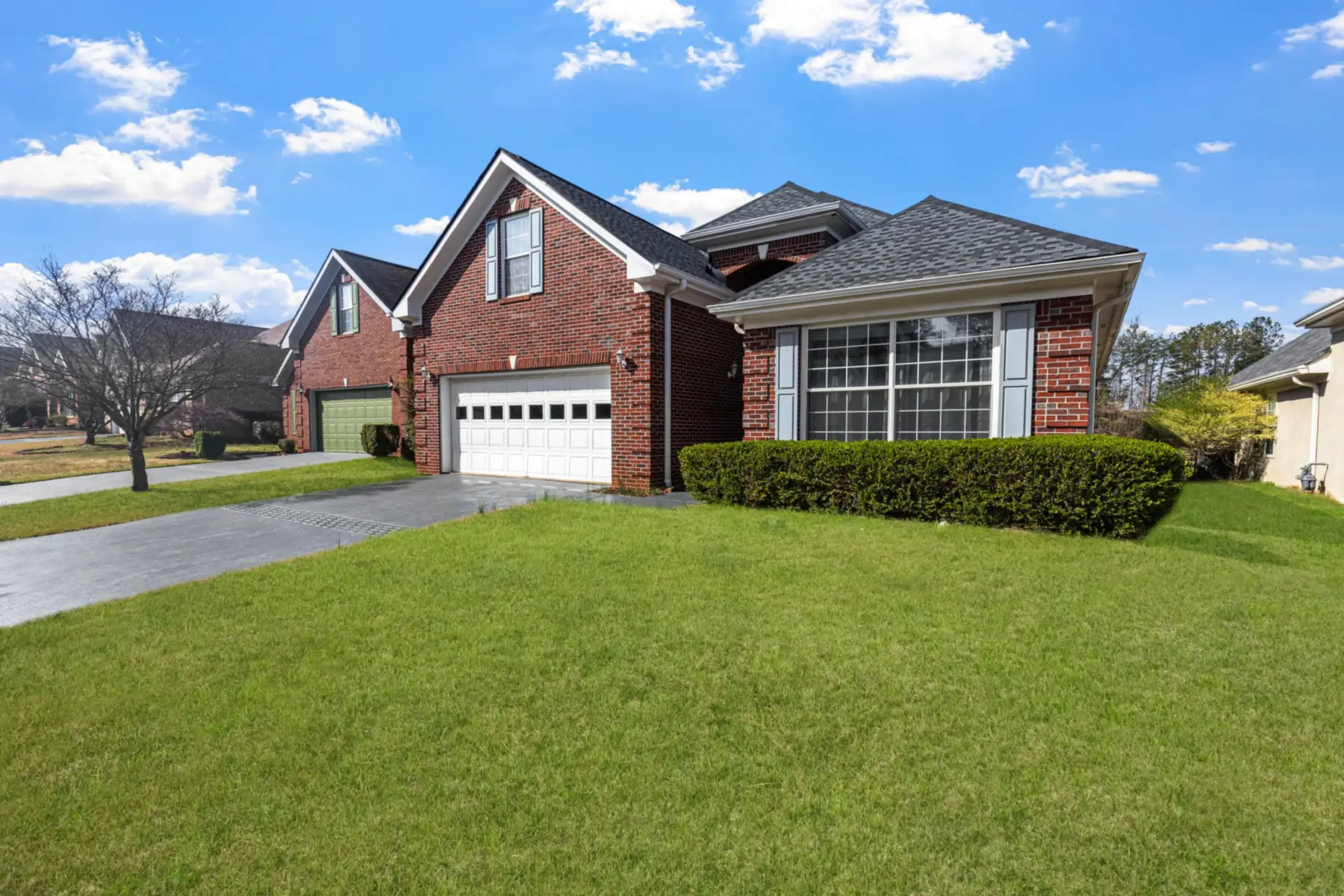 A brick Texas home with a composite shingle roof, framed by mature trees