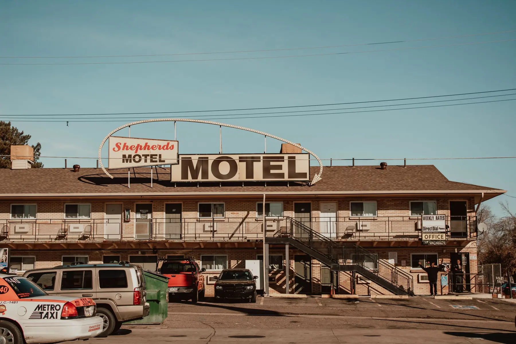 A two-story exterior-corridor hotel with a pitched shingle roof