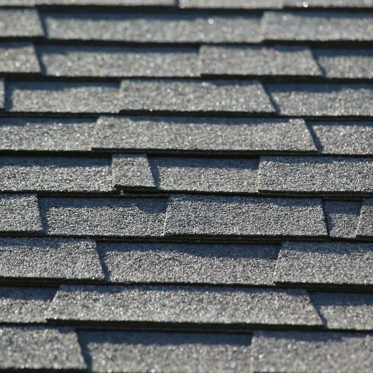 Close view of a sound asphalt shingle roof: flat tabs lying tight, dense unbroken granule coverage, even color